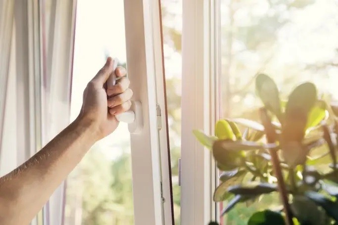 Nahaufnahme einer Hand, die ein modernes Kunststofffenster zur Belüftung öffnet